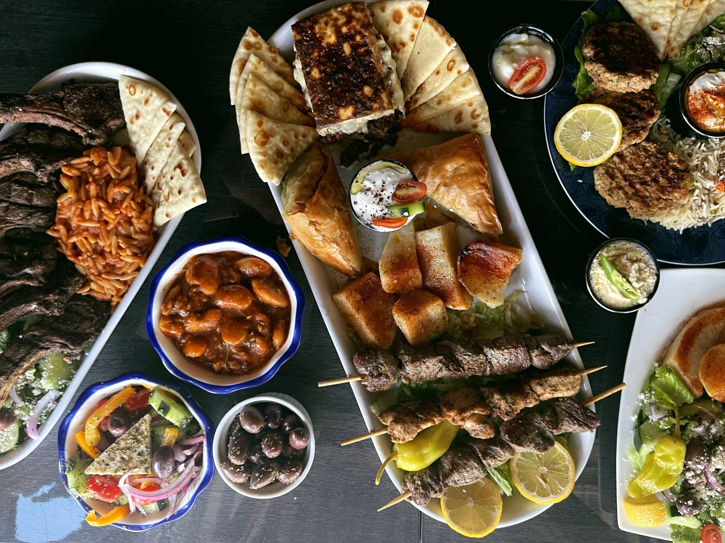 Greek platters with souvlaki, pita, salad, dips, and grilled meats